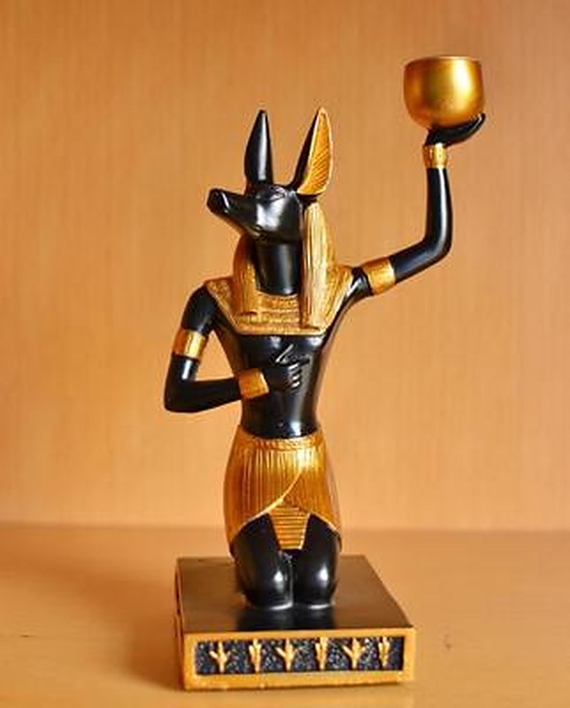 Statue-bougeoir Anubis en résine noir et or, dieu à tête de chacal agenouillé tenant une coupelle dorée — cabinet de curiosités Curiosa